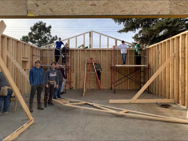 students posing in a framed they are helping build